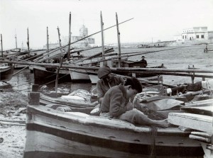 Porto peschereccio di Trapani, anni ‘50; pescatori cuciono le reti a bordo dei gozzi (foto propr. Tonino Perrera)