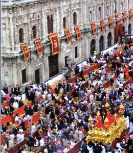 Spettatori paganti variamente occupati mentre per la carrera oficial transita un paso (@ J. A. Zamora, Pasiones. Semana Santa en Sevilla).