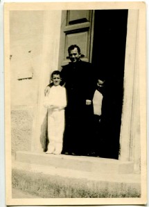 Fiamignano 8 maggio 1964, il giorno prima della partenza. Prima comunione di Settimio, con Don Cesare Federici sulla porta della chiesa (ph archivio B. Adriani).