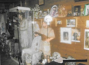 Sull'altare della chiesa, la statua di san Giovanni Battista e di Emilia, Padre Pio e foto di defunti di pellegrini