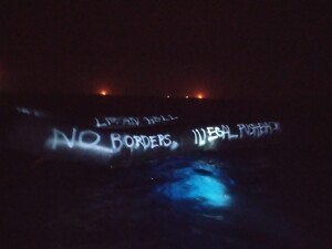 Un gommone trovato vuoto, perché la guardia costiera libica aveva effettuato un respingimento pochi minuti prima, sotto gli occhi della ONG. Dietro, le fiamme di alcune piattaforme petrolifere a largo delle coste della Libia. L'equipaggio della nave ONG segna sempre con la bomboletta le barche così che eventuali altri soggetti che le trovino vuote sappiano che destino hanno incontrato (ph. J. Iozzelli, ottobre 2021)