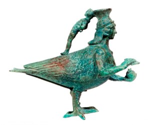 Askos in bronzo a forma di sirena dalla necropoli delle Murgie di Strongoli (antica Petelia), Museo Nazionale di Crotone. Nel manico del vaso unguentario è raffigurata l’anima del defunto che il demone ha il compito di portare con sé in cielo. Tra le mani della Sirena una melagrana, frutto infero che simboleggia la fertilità e la rinascita, e il flauto di Pan, le cui sette canne corrispondono ai sette pianeti e la cui funzione musicale rimanda all’armonia dei sette suoni che costituiscono l’ottava, la consonanza perfetta. Immagine ed informazioni prelevate dall’articolo “Sul dorso della sirena. La Crotone pitagorica in alcuni capolavori d’arte funeraria” di Margherita Corrado