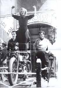 5.Luisella Biamino, artista acrobatica, si esibiva nello spettacolo Il Muro della Morte, che come è noto consisteva di evoluzioni in motocicletta, in una piccola pista circolare fortemente inclinata verso l’interno: in questa immagine, ripresa al di fuori del padiglione, la Loy è in piedi su di una moto insieme a due compagni di lavoro. Cottino aveva temporaneamente introdotto nello spettacolo alcuni leoni, collocati nella buca centrale, mentre i motociclisti volteggiavano sulle pareti del Muro, sporgendosi pericolosamente verso gli animali.